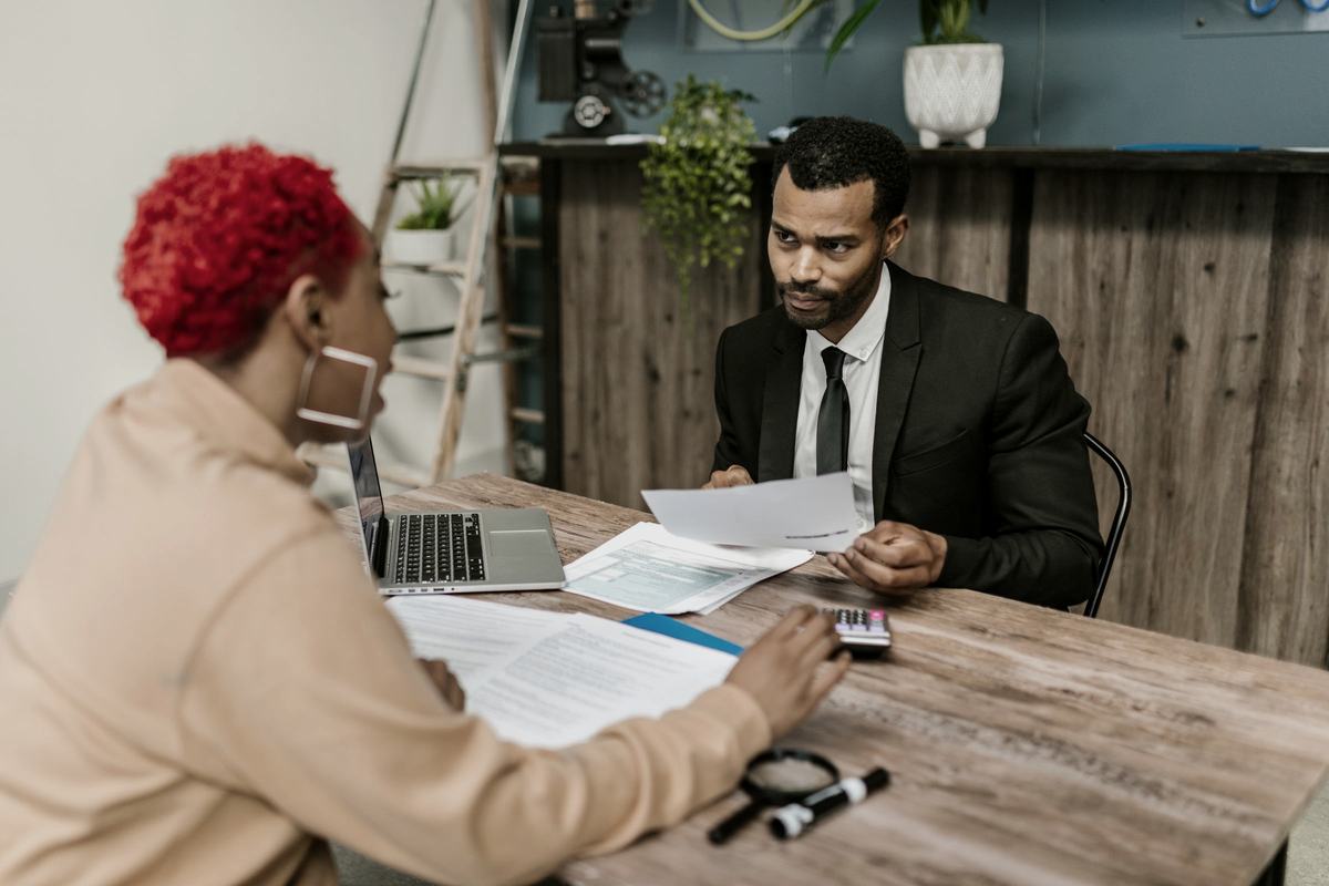 An adviser and a business owner reviewing financial documents together across a table