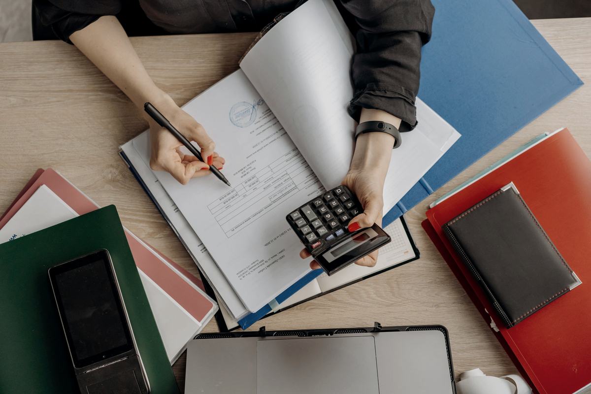 An accountant working through figures with a calculator and printed ledgers