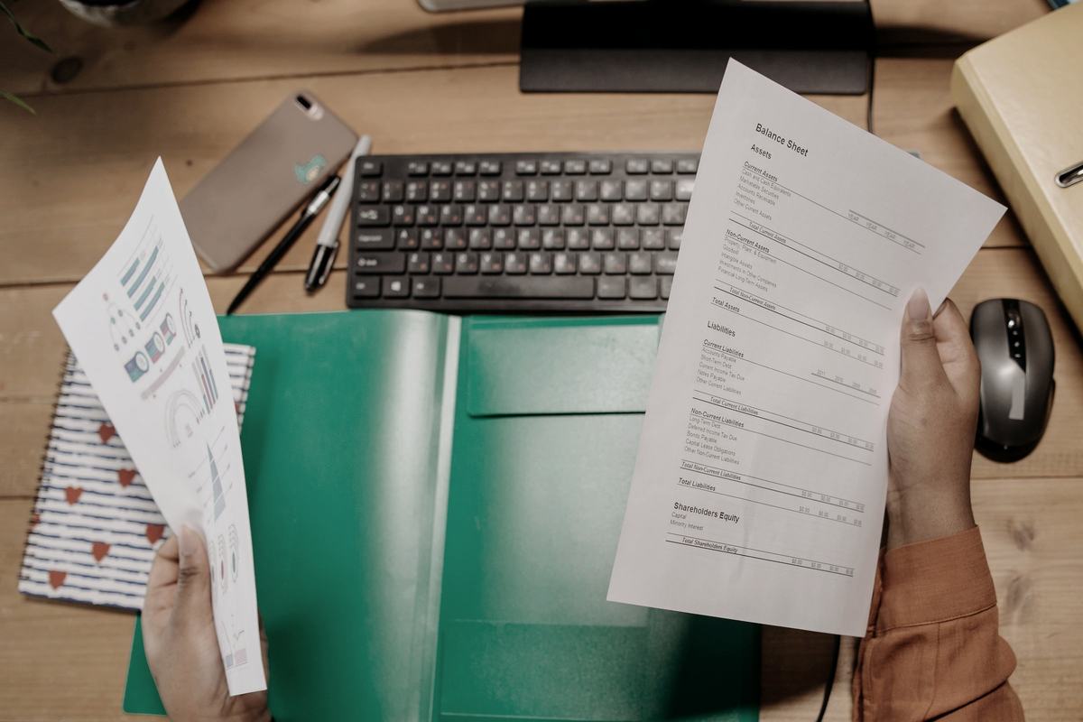 Hands reviewing a printed balance sheet and supporting schedules at a desk